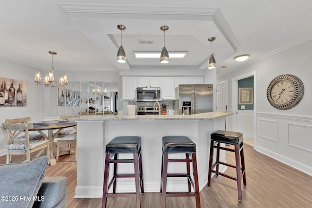 kitchen with appliances with stainless steel finishes, light wood-style floors, visible vents, and a kitchen breakfast bar