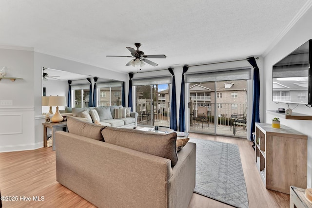 living area with light wood-type flooring, plenty of natural light, and ceiling fan