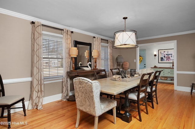 dining area featuring light wood finished floors, baseboards, and crown molding