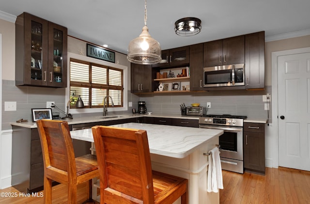 kitchen with dark brown cabinetry, glass insert cabinets, stainless steel appliances, crown molding, and a sink