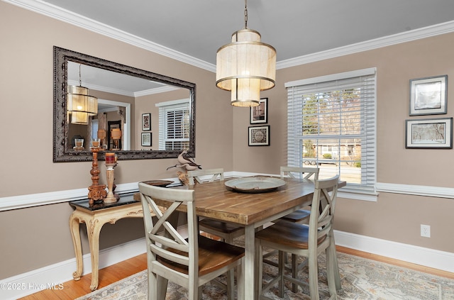 dining area with baseboards, crown molding, and light wood finished floors