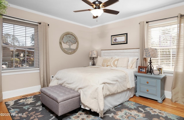 bedroom with multiple windows, ornamental molding, and wood finished floors