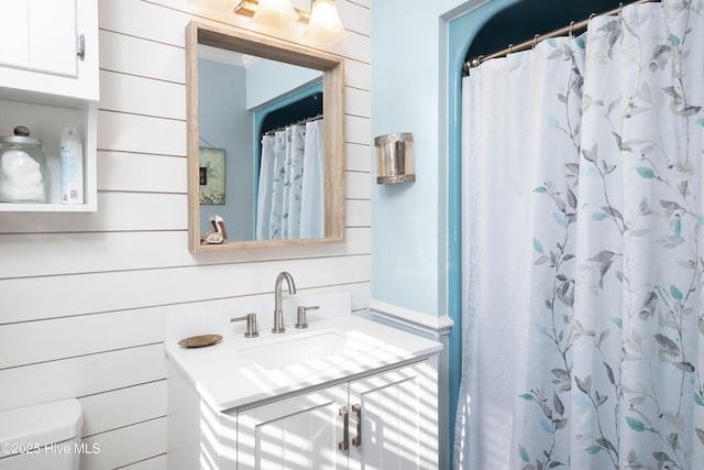 full bath featuring wooden walls, vanity, and toilet