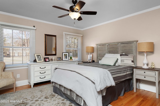 bedroom with light wood-style floors, crown molding, baseboards, and ceiling fan