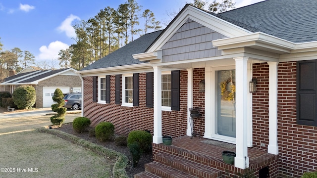 exterior space with driveway, a shingled roof, and brick siding