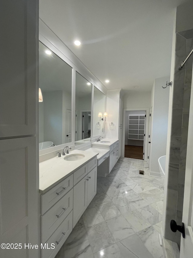 full bathroom with marble finish floor, a freestanding tub, two vanities, and a sink