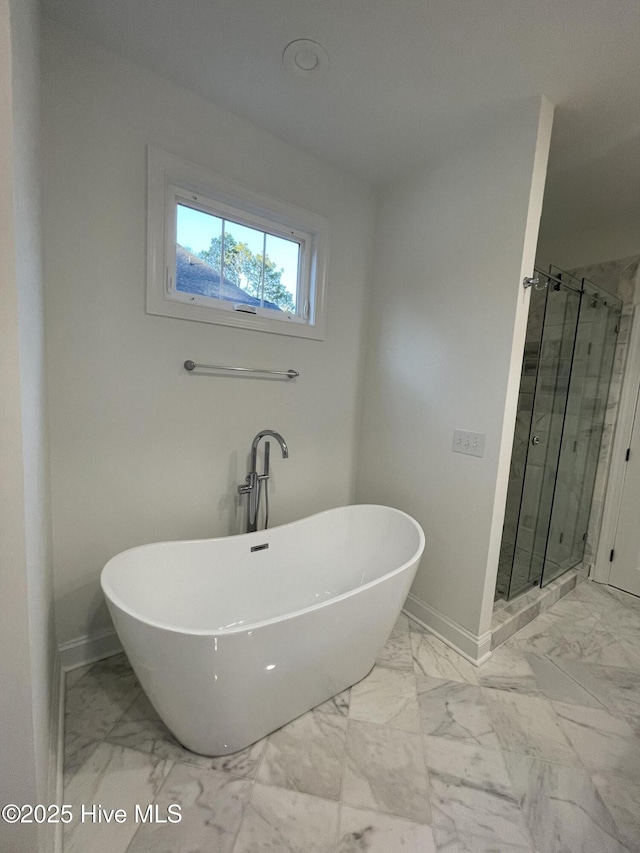 bathroom with marble finish floor, a shower stall, baseboards, and a freestanding tub