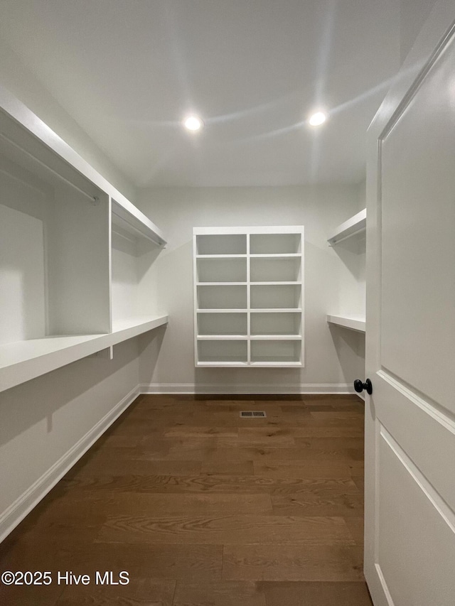 walk in closet with dark wood-style flooring