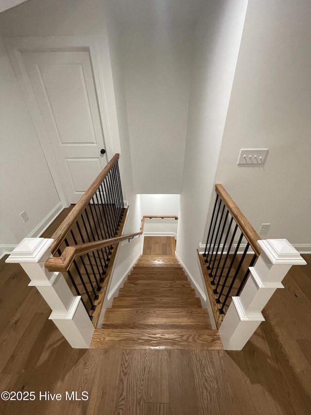 staircase with baseboards and wood finished floors