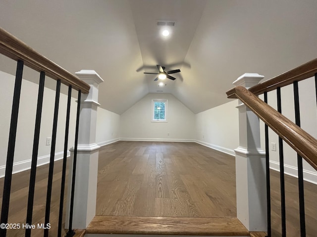 additional living space featuring dark wood-style floors, lofted ceiling, visible vents, and stairs