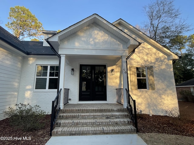 entrance to property with french doors, brick siding, and board and batten siding