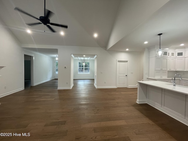 interior space featuring lofted ceiling, glass insert cabinets, white cabinets, light countertops, and decorative light fixtures