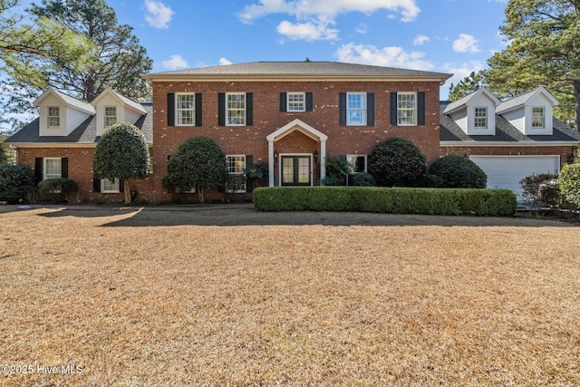 view of front of home with a front yard, brick siding, and an attached garage