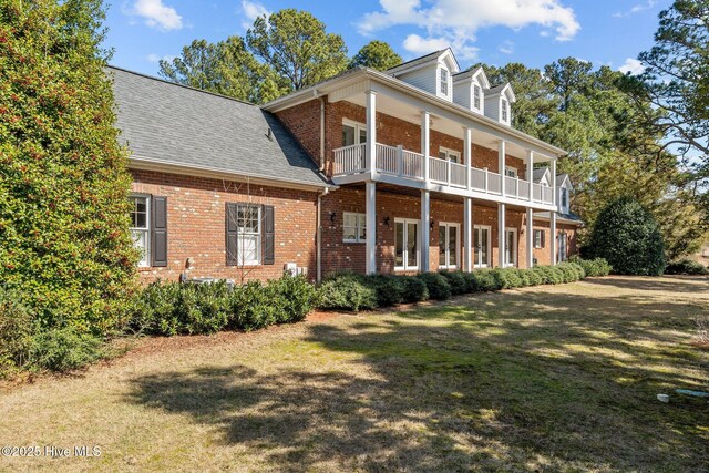 28 Beasley Dr, Pinehurst, NC 28374 - back of house featuring brick siding, a balcony, a yard, and roof with shingles