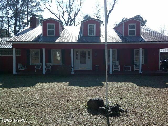 view of front of property featuring covered porch, a chimney, and metal roof