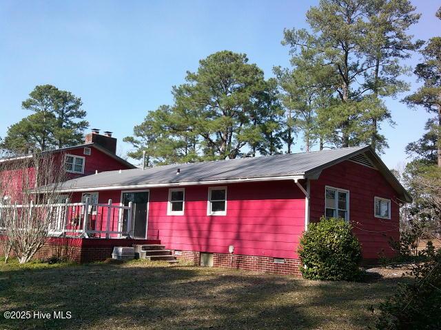 rear view of property with a yard, a chimney, and a wooden deck