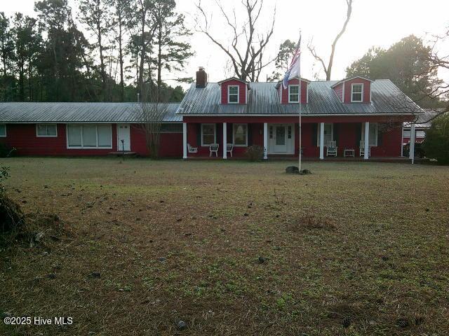 view of front of property with covered porch, metal roof, and a front lawn