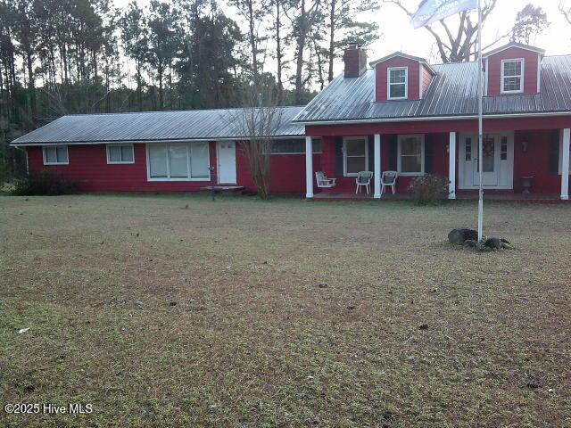 view of front of home featuring metal roof, a front lawn, a porch, and cooling unit