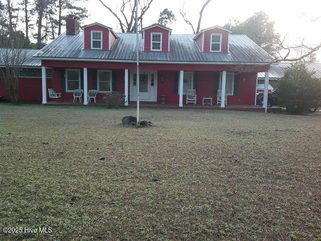 view of front of home with a front yard, covered porch, and metal roof