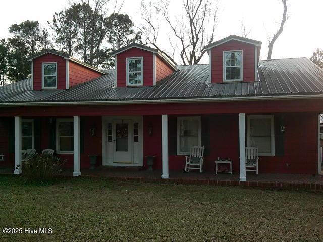 view of front of house with covered porch, metal roof, and a front yard