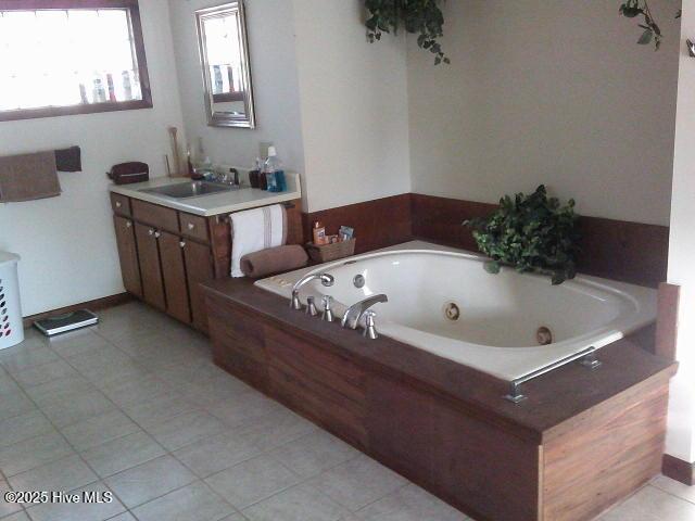 bathroom with tile patterned flooring, a jetted tub, and vanity