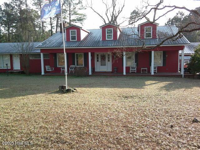 view of front facade with a porch, metal roof, and a front lawn