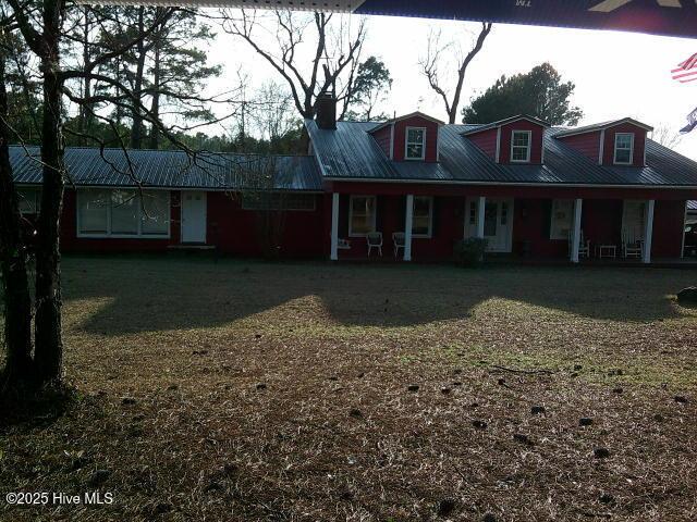 view of front of house featuring a porch, metal roof, and a front lawn