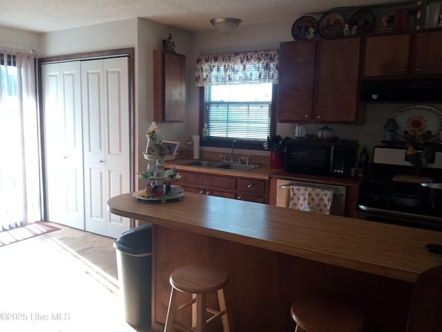 kitchen with range, dishwashing machine, range hood, black microwave, and wooden counters