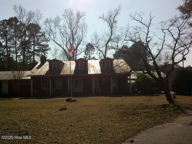 back of house featuring metal roof and a yard