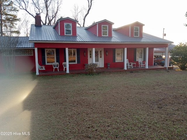 view of front of house featuring covered porch, metal roof, and a front yard