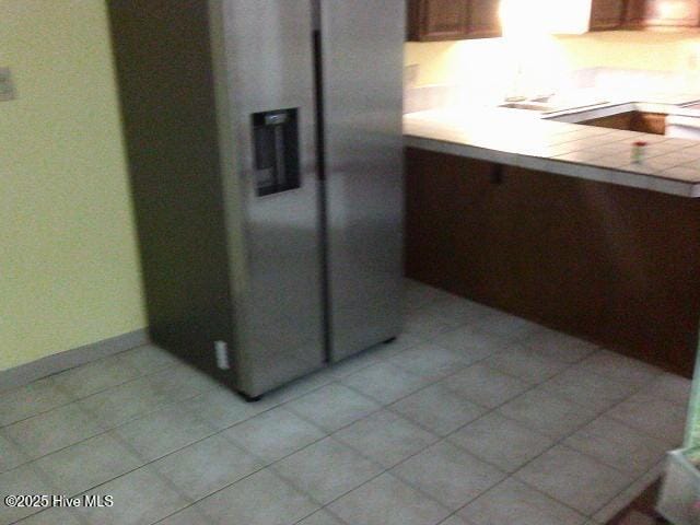 kitchen featuring tile countertops, baseboards, light tile patterned flooring, and stainless steel fridge with ice dispenser