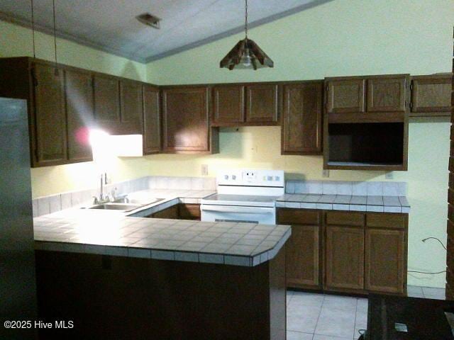 kitchen featuring lofted ceiling, a peninsula, a sink, tile counters, and white range with electric stovetop