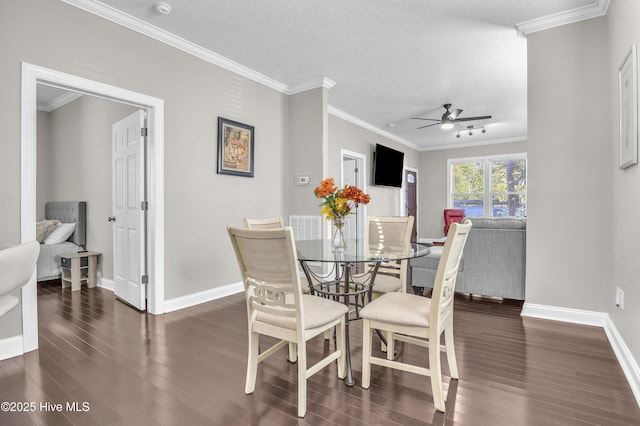 dining space with dark wood-type flooring, crown molding, baseboards, and ceiling fan