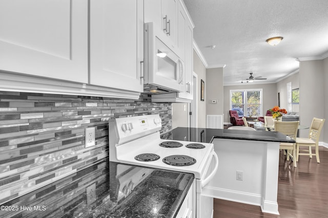 kitchen with tasteful backsplash, dark countertops, white appliances, and white cabinetry