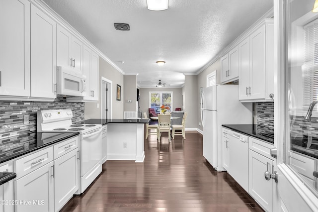 kitchen with dark countertops, white appliances, white cabinets, and dark wood finished floors