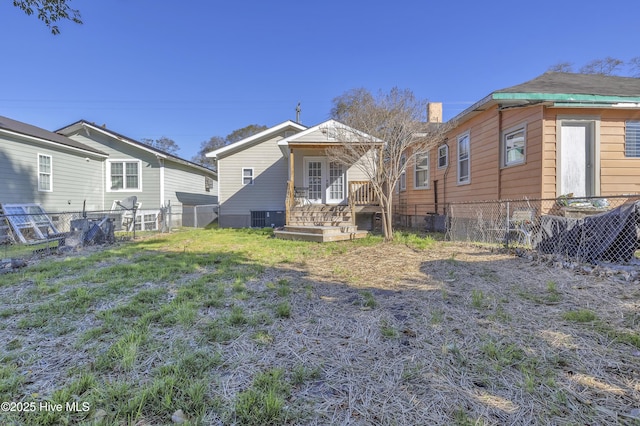 rear view of property with central AC, a yard, and fence