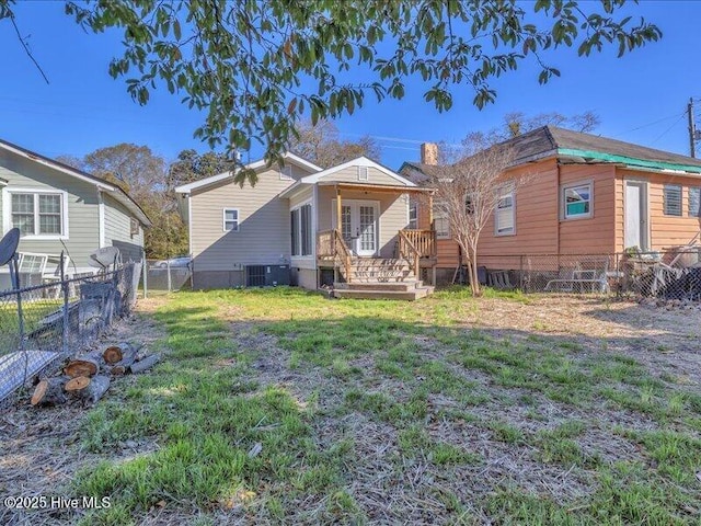 rear view of house with a yard, central AC unit, a chimney, and fence private yard