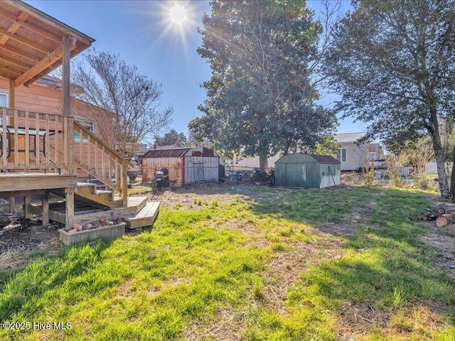 view of yard featuring a deck, a shed, an outdoor structure, and stairs