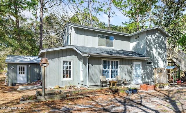 rear view of property featuring a shingled roof and a vegetable garden