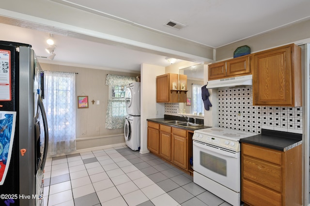 kitchen featuring visible vents, stainless steel fridge with ice dispenser, under cabinet range hood, electric stove, and stacked washer / drying machine