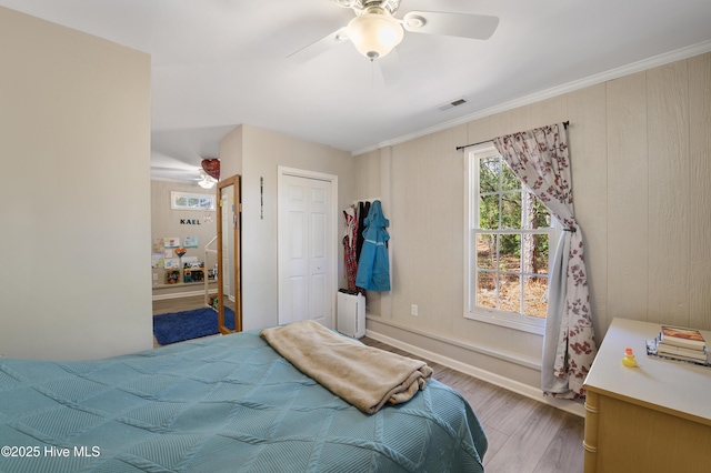 bedroom with visible vents, ceiling fan, ornamental molding, wood finished floors, and a closet