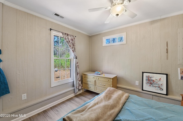 bedroom featuring visible vents, a ceiling fan, wood finished floors, and crown molding