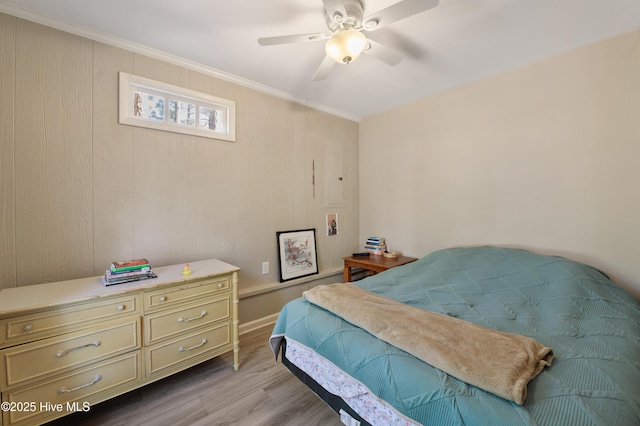 bedroom featuring a ceiling fan, crown molding, and light wood-style floors