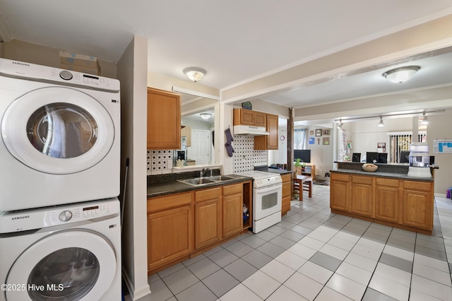 kitchen featuring electric range, a sink, stacked washer and dryer, under cabinet range hood, and dark countertops