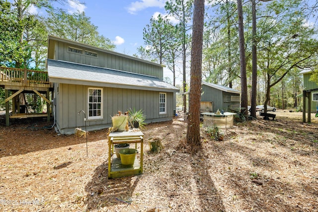 back of property with a deck, stairway, and a shingled roof