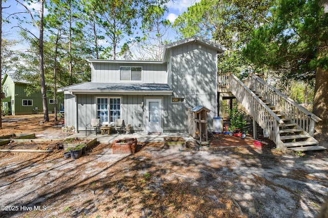 view of front of house featuring stairway, a patio area, and a shingled roof