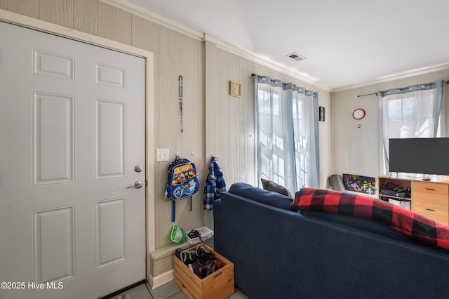 living room featuring a wealth of natural light, visible vents, and ornamental molding