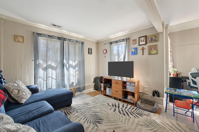 tiled living room featuring beam ceiling, baseboards, visible vents, and ornamental molding