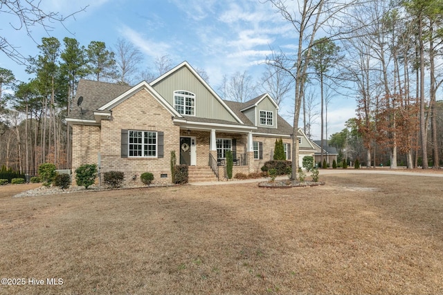 craftsman-style house featuring covered porch, brick siding, a shingled roof, crawl space, and a front lawn