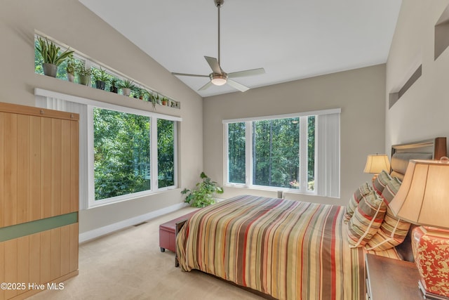 bedroom featuring lofted ceiling, light carpet, baseboards, and multiple windows